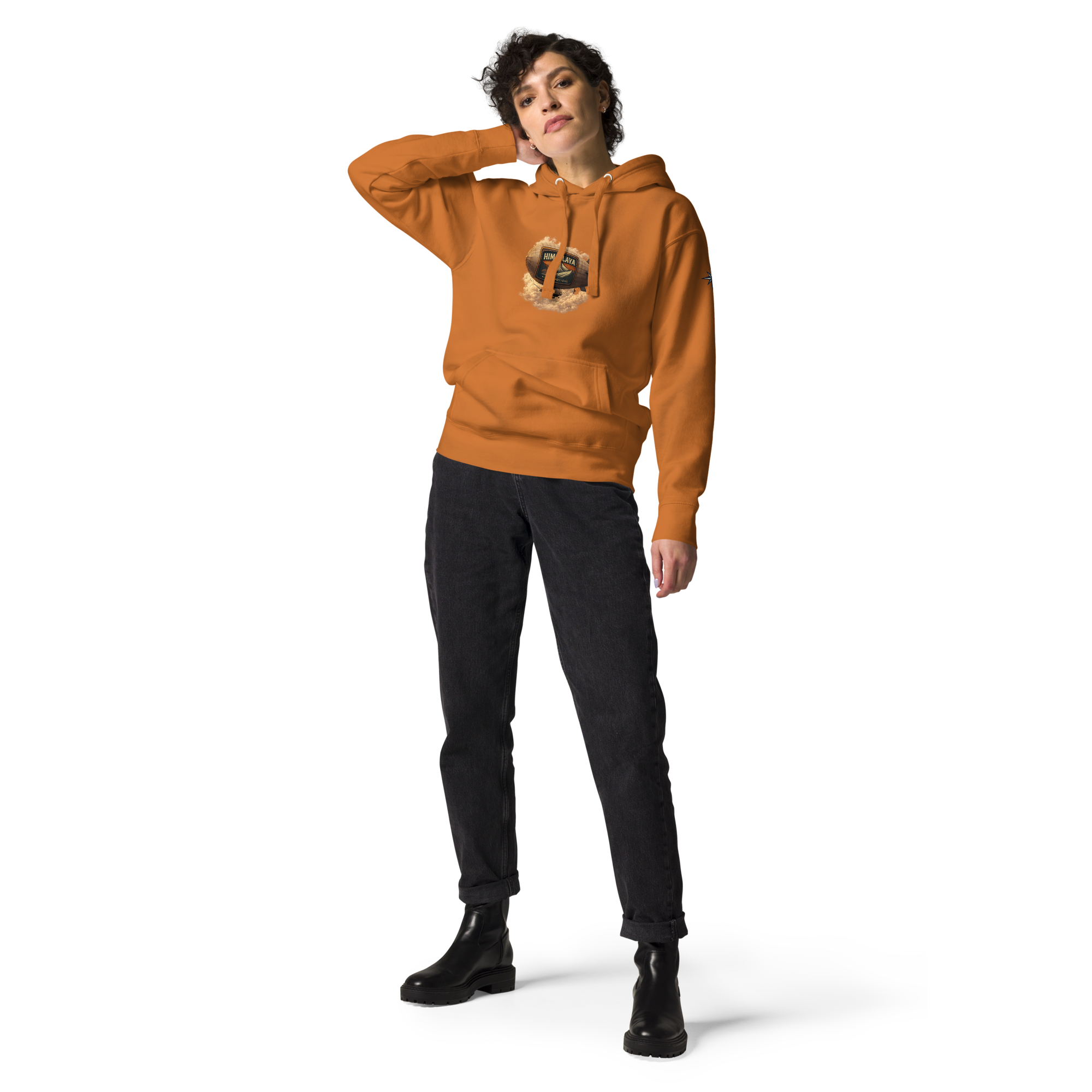 Person wearing an orange hoodie with a HIMAPLAYA logo on the chest , black jeans and boots